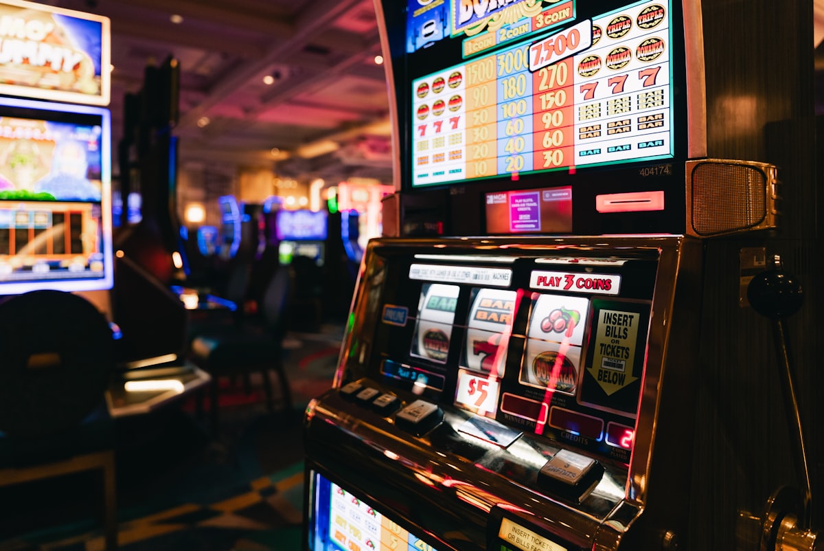 Deretan mesin slot di aula kasino dengan pencahayaan redup